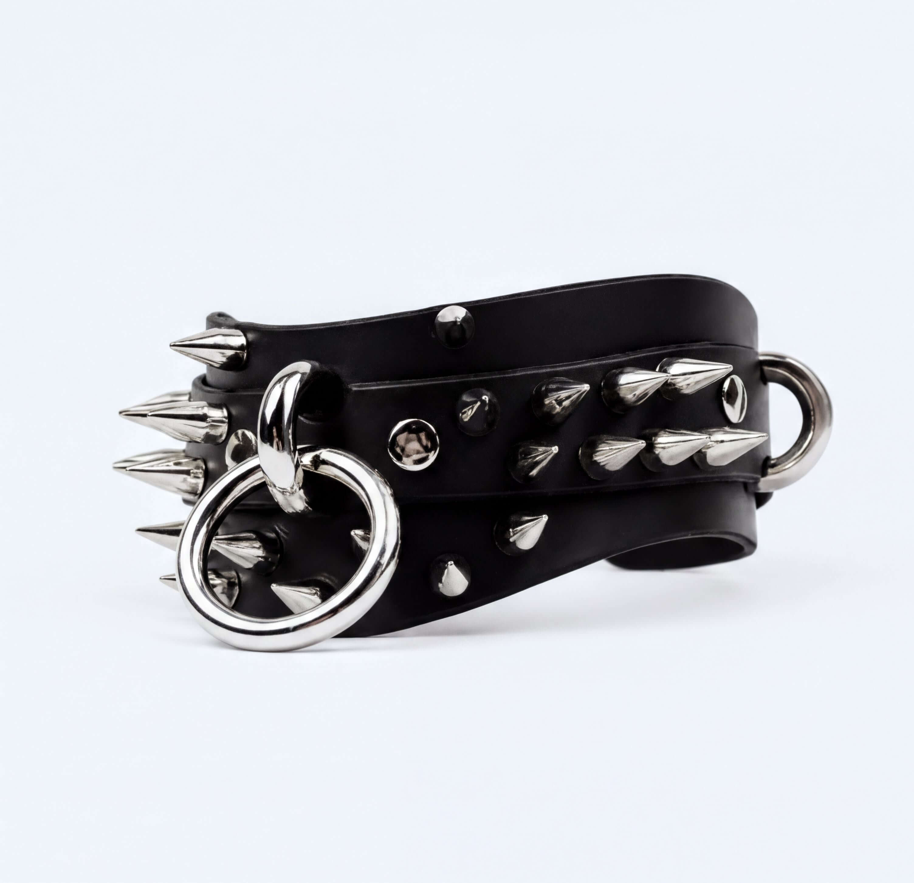 A black leather bracelet with silver spikes and rings, creating a bold and edgy appearance.