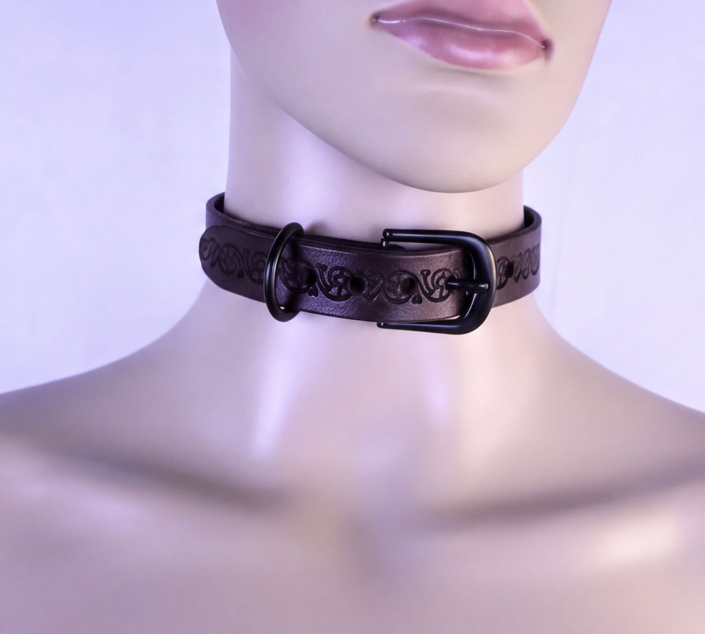 A mannequin wearing a black leather choker necklace with a decorative buckle.