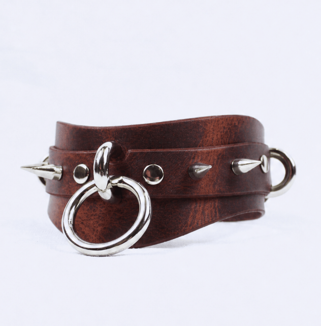 A brown leather choker necklace with silver metal spikes protruding from it.
