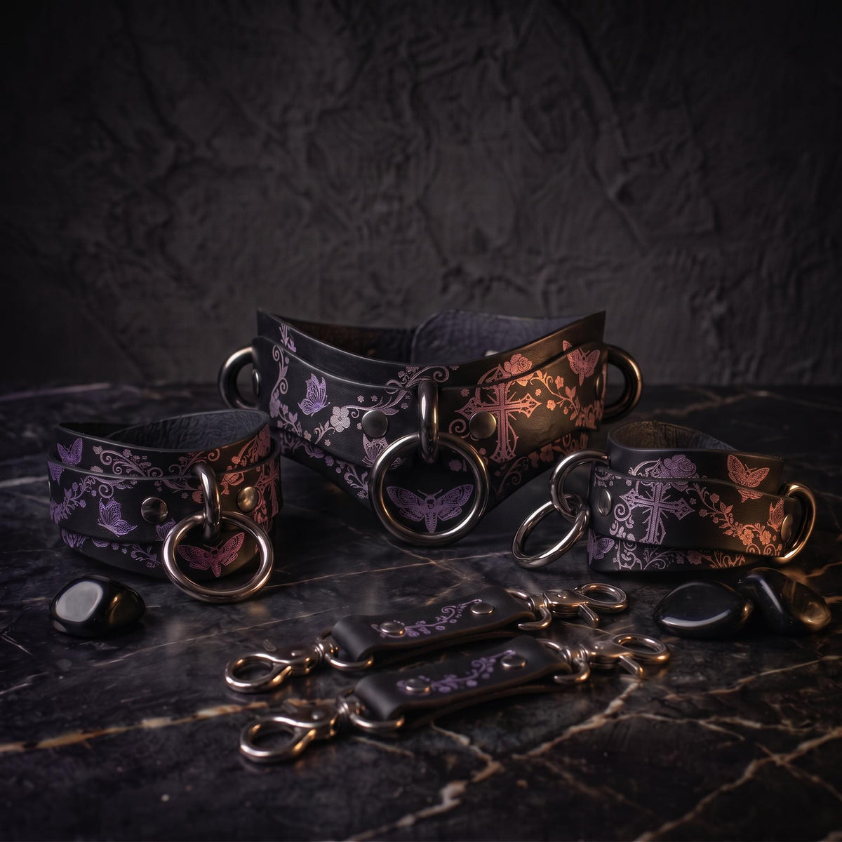 a collection of leather straps and charms with floral and butterfly designs, arranged on a dark surface.