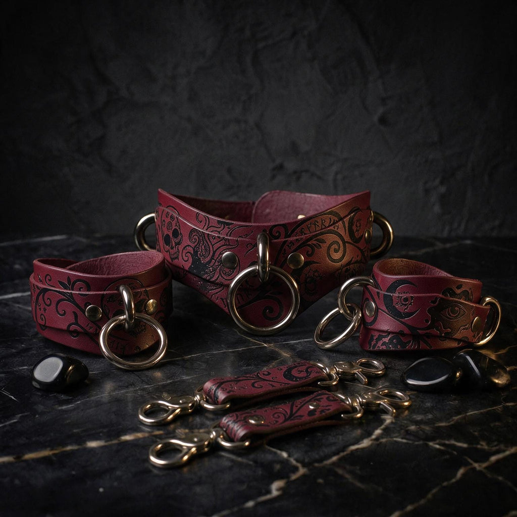 A collection of burgundy leather straps with intricate black designs, arranged on a dark surface.