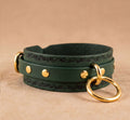 A green leather choker necklace with gold metal rings and a decorative leaf pattern on the front.