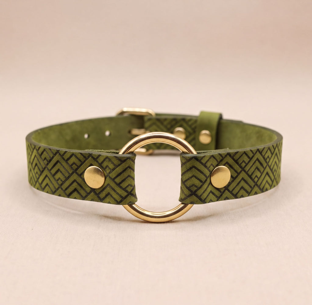 A green leather collar with a gold-colored metal ring and two gold-colored metal fasteners.