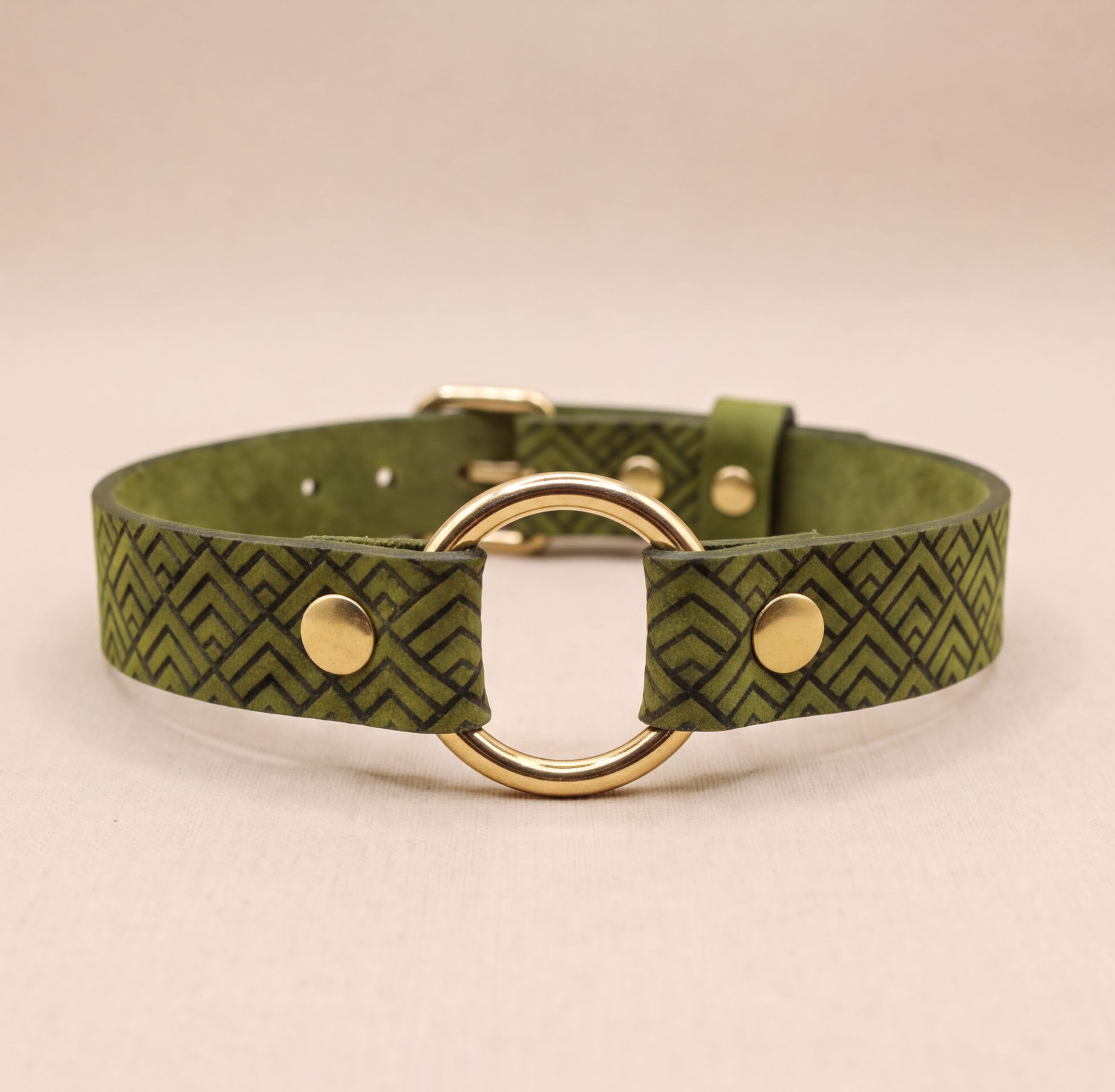A green leather collar with a gold-colored metal ring and two gold-colored metal fasteners.