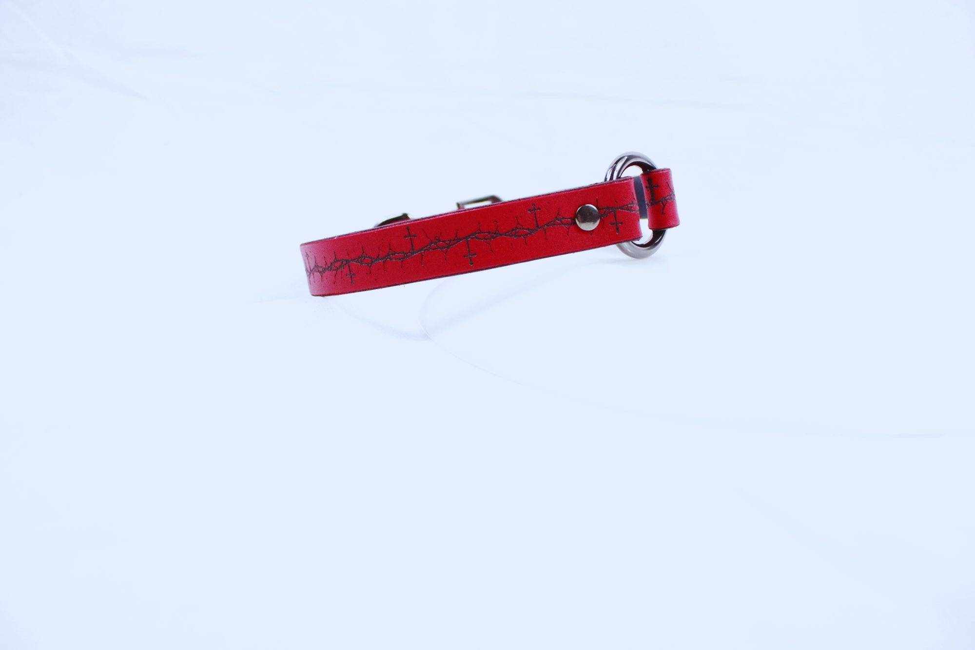 A red leather dog collar with a metal buckle and a black design on the surface.