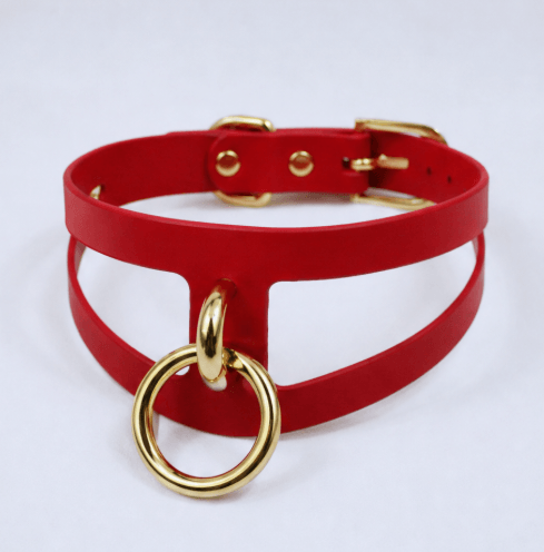 A red choker necklace with a gold ring and buckle detail.