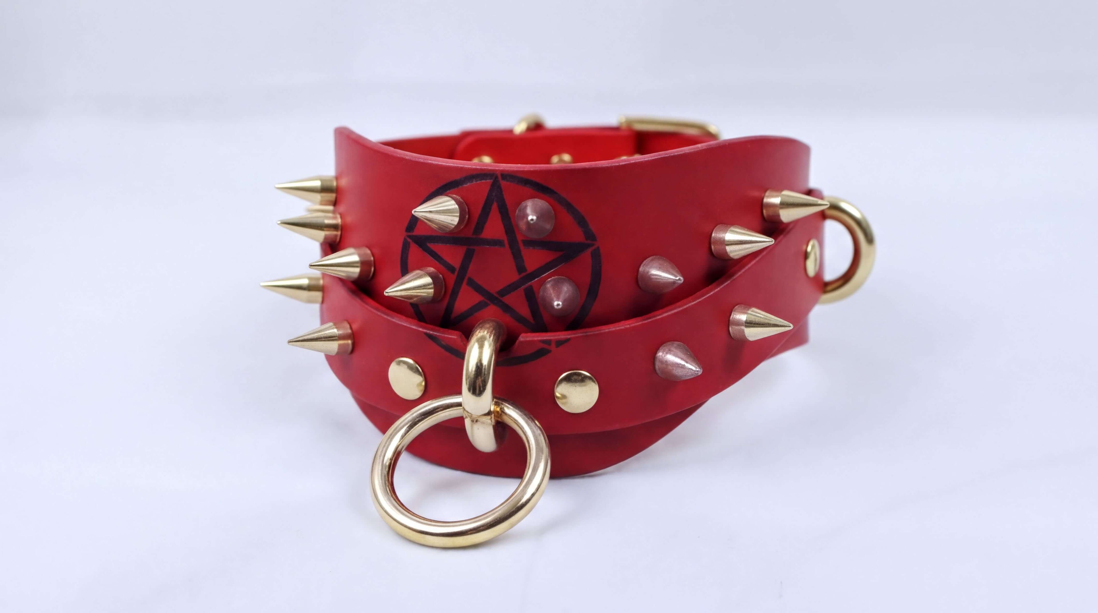A red leather collar with spikes and a pentagram symbol on it.