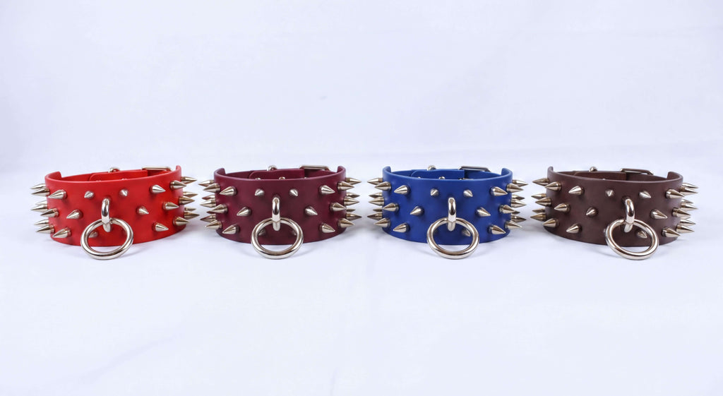 Four leather cuffs with spikes on them, arranged in a row against a white background.