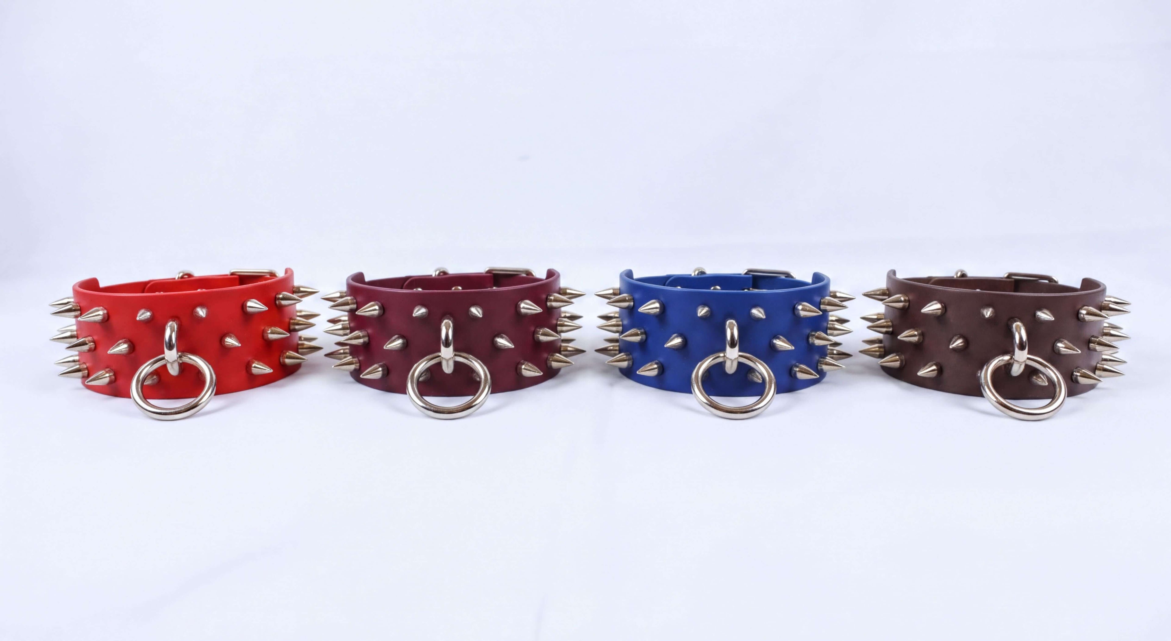 Four leather cuffs with spikes on them, arranged in a row against a white background.