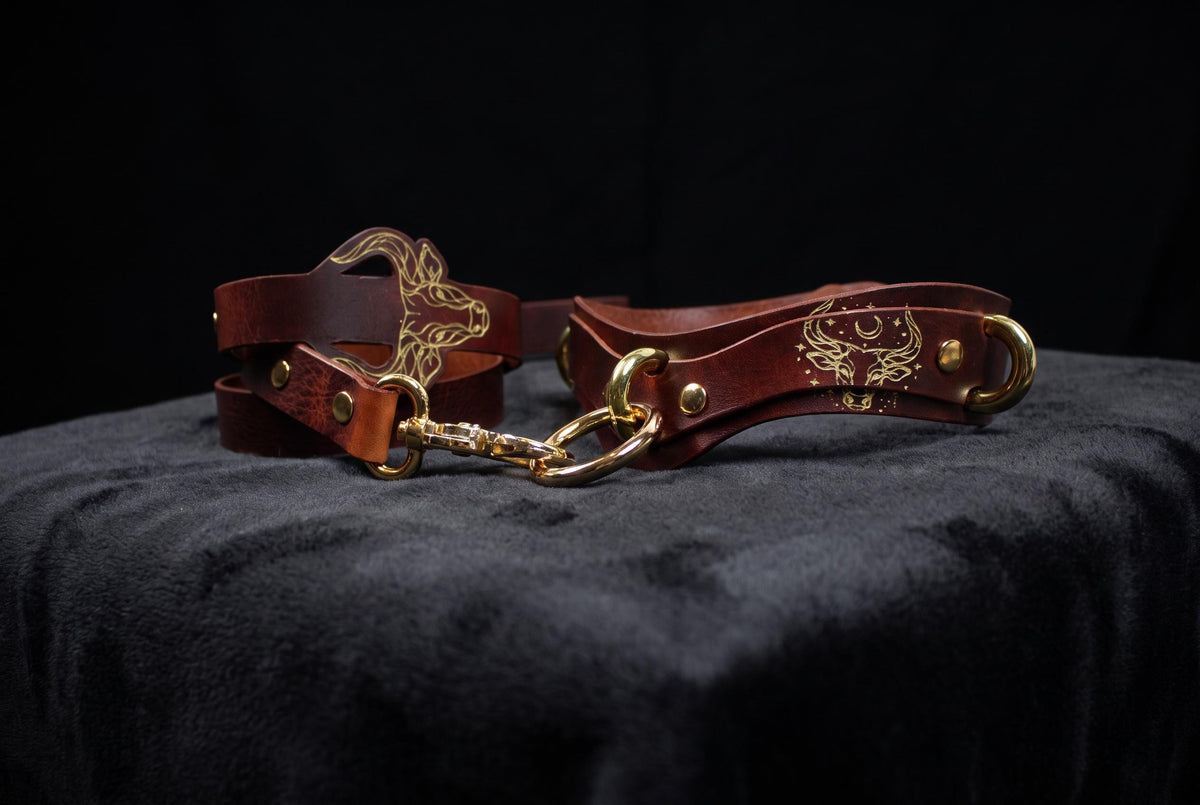 A brown leather strap with a gold buckle and a gold-colored buckle is displayed against a black background.