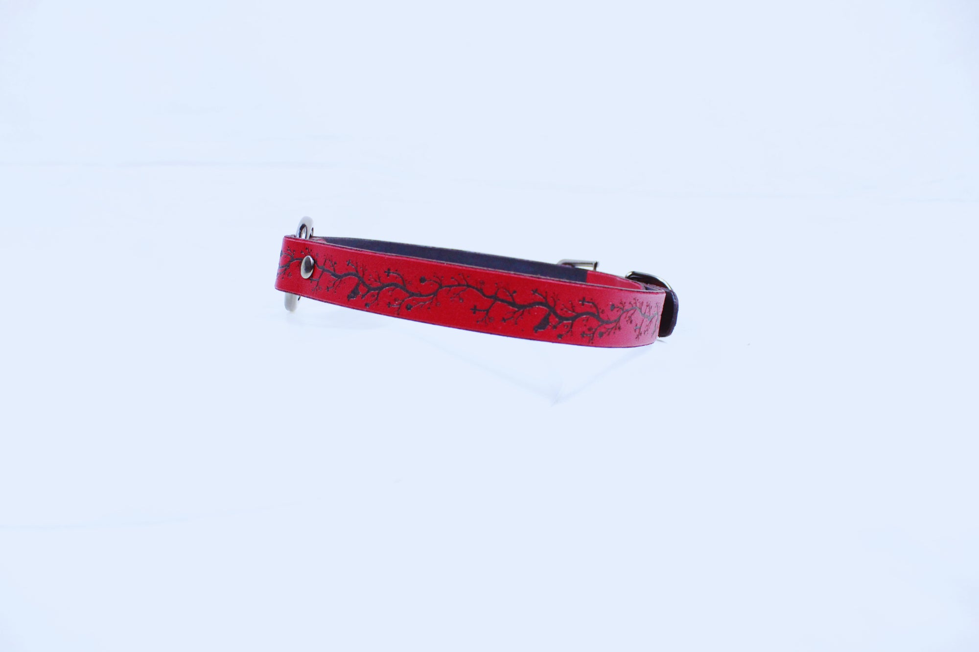 A red dog collar with a black design on it is shown against a white background.