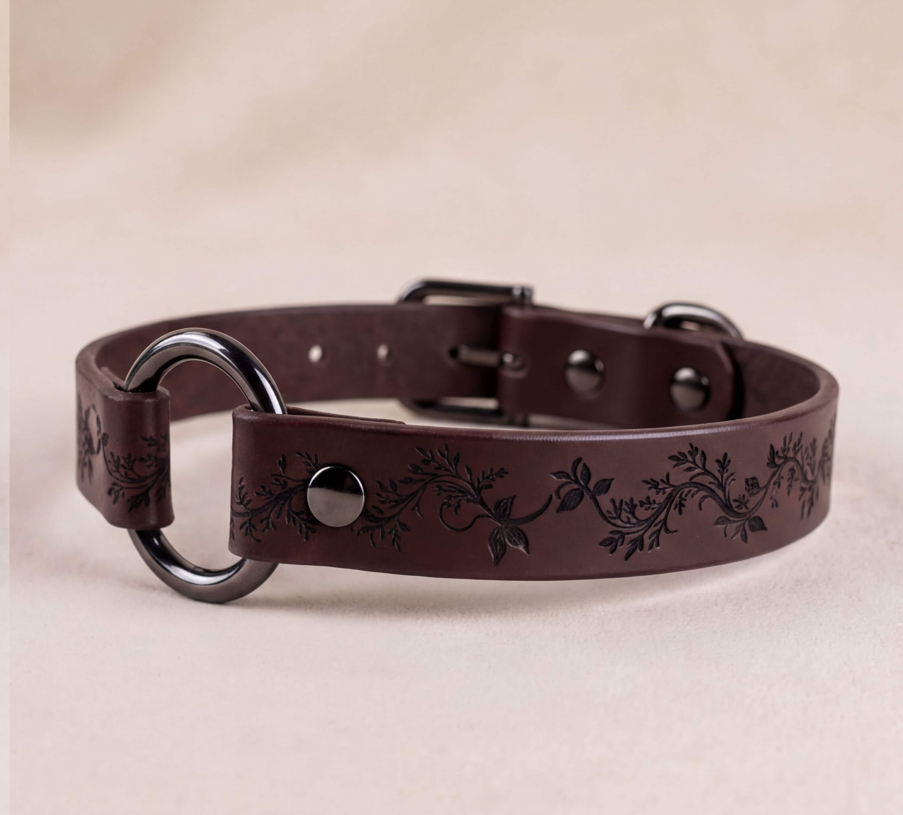 A brown leather dog collar with a floral pattern and metal rings.