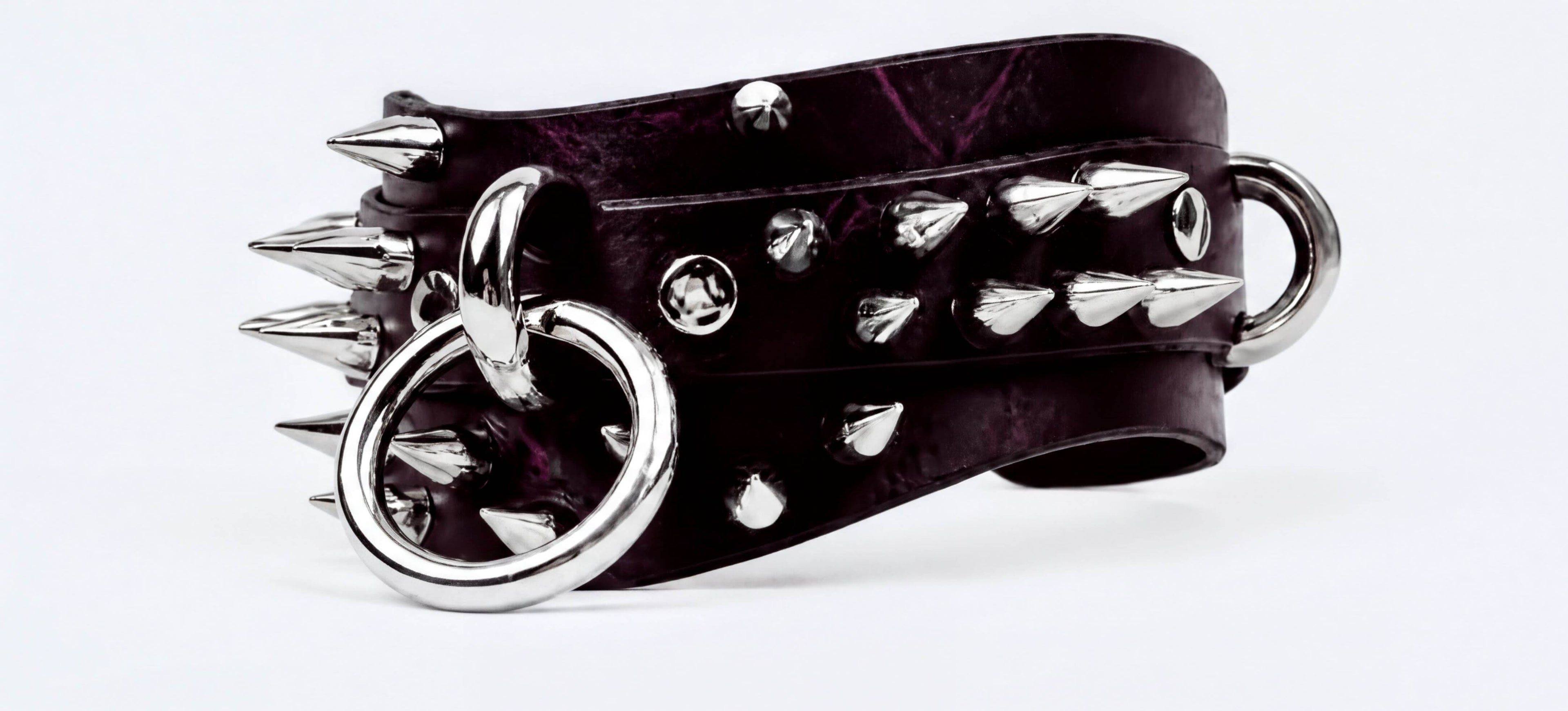 A close-up image of a black leather bracelet with silver spikes and rings, creating a bold and edgy appearance.