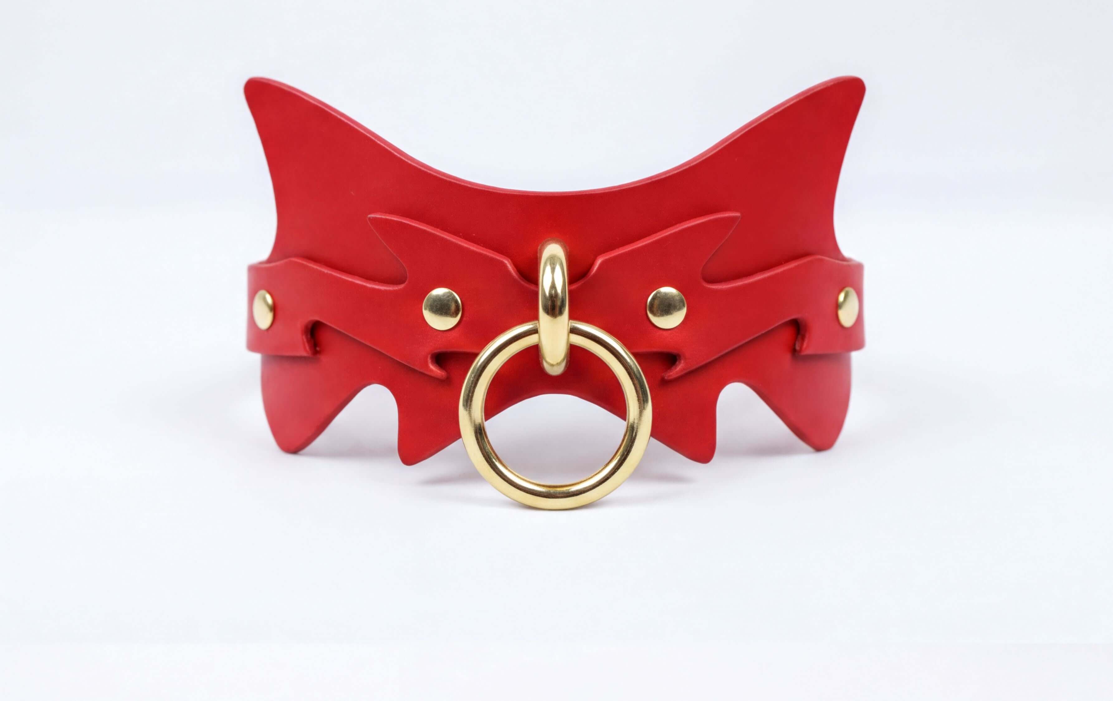 A red leather collar with a gold ring and a unique, cat-like design.