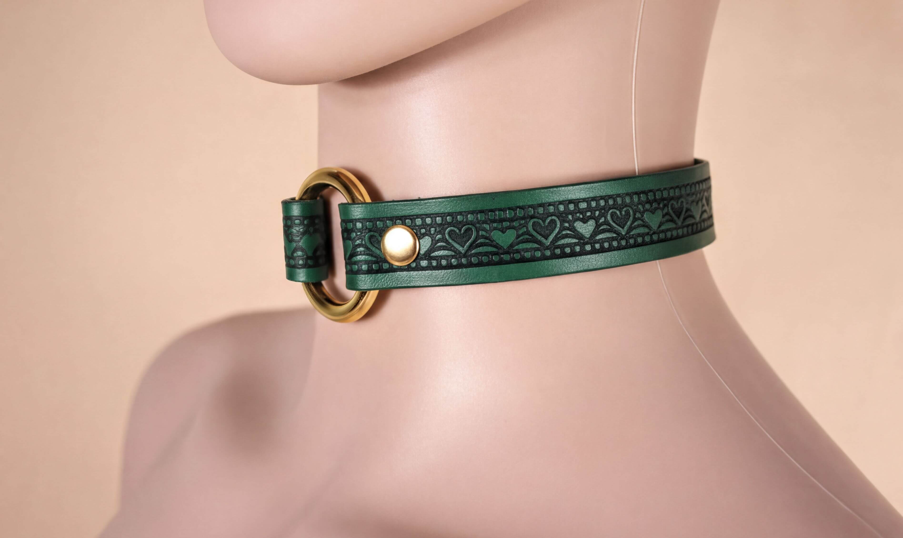 A mannequin head wearing a green leather choker necklace with a gold-colored buckle.