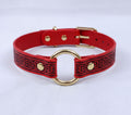 A red and black patterned choker necklaces with a gold ring and buckle.