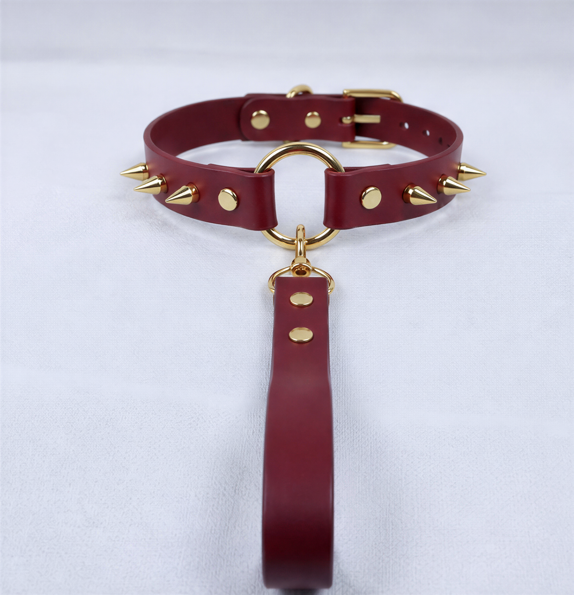 A burgundy leather choker collar with gold studs and a gold-colored metal clasp.