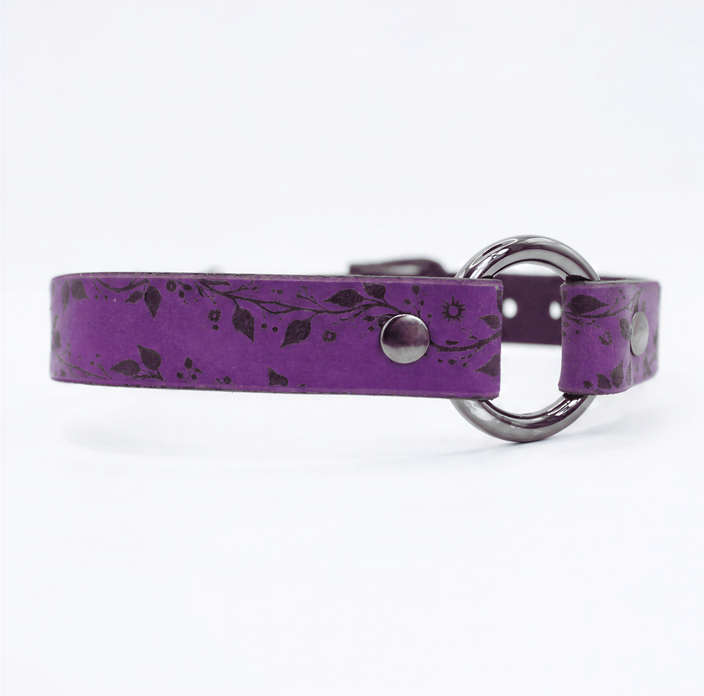 A purple leather collar with a silver metal ring and leaf pattern design.
