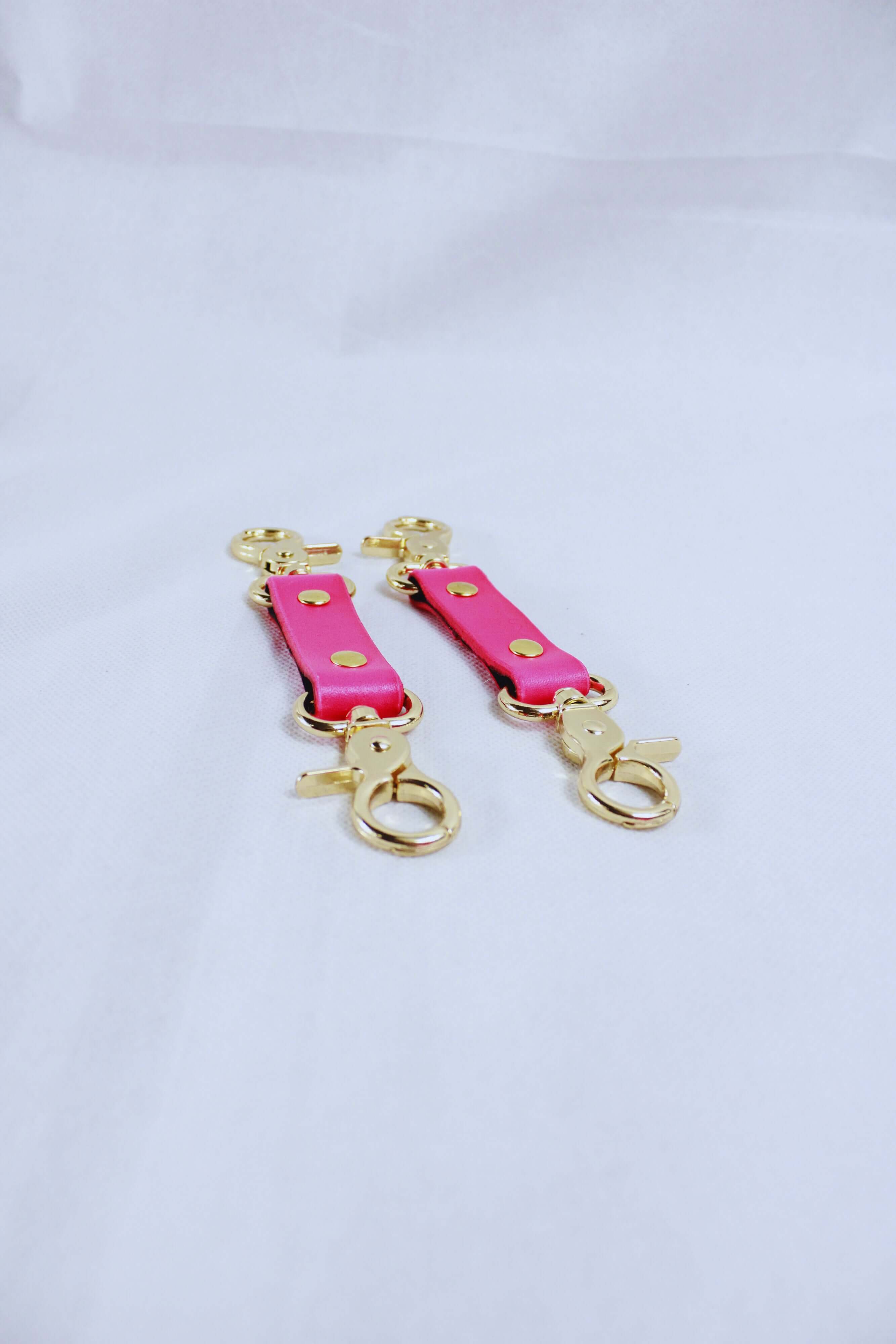 Pink bondage connectors with gold hardware for BDSM gear and sub collars, ideal for enhancing your erotic adventures.