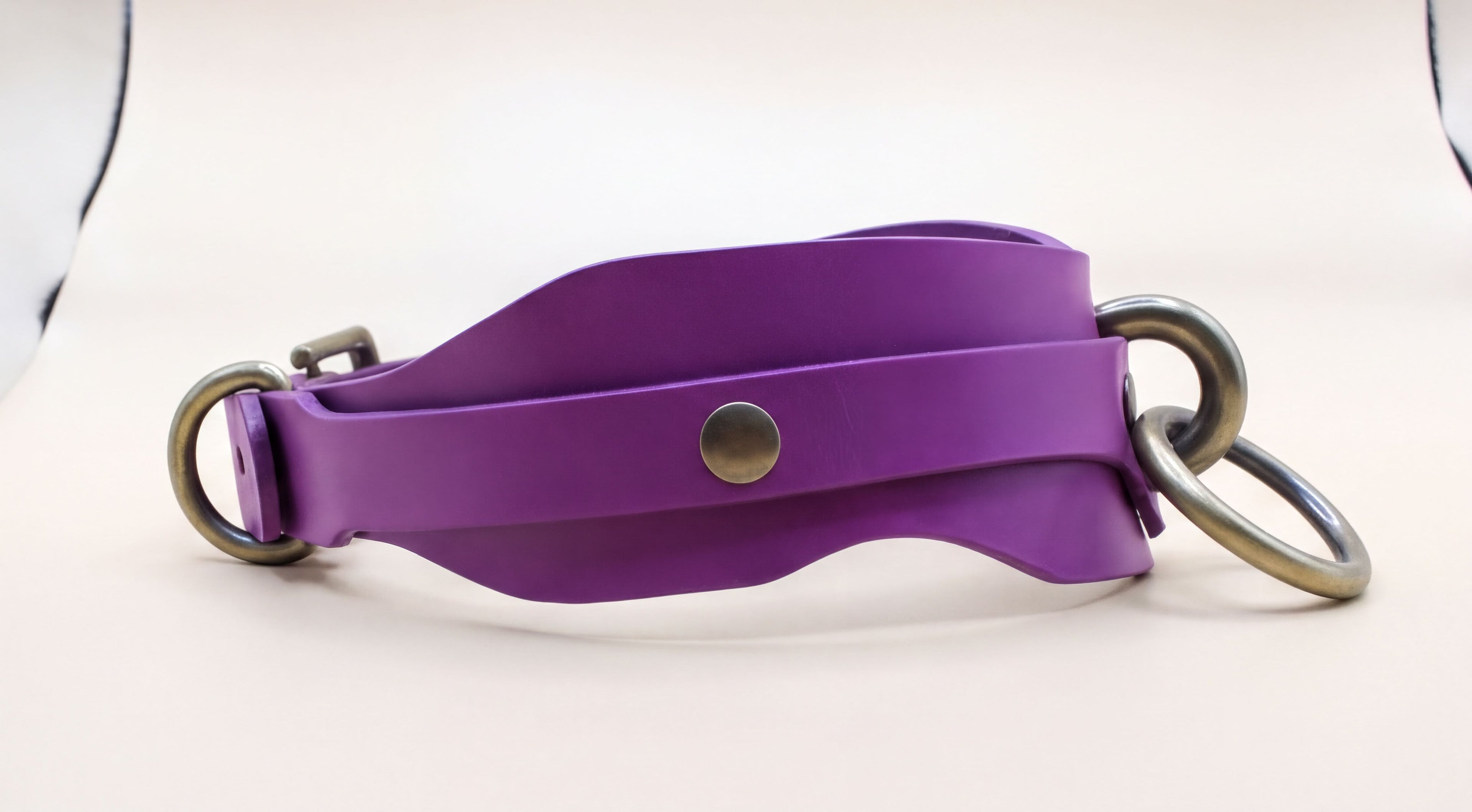 A purple leather strap with metal rings and a button closure.