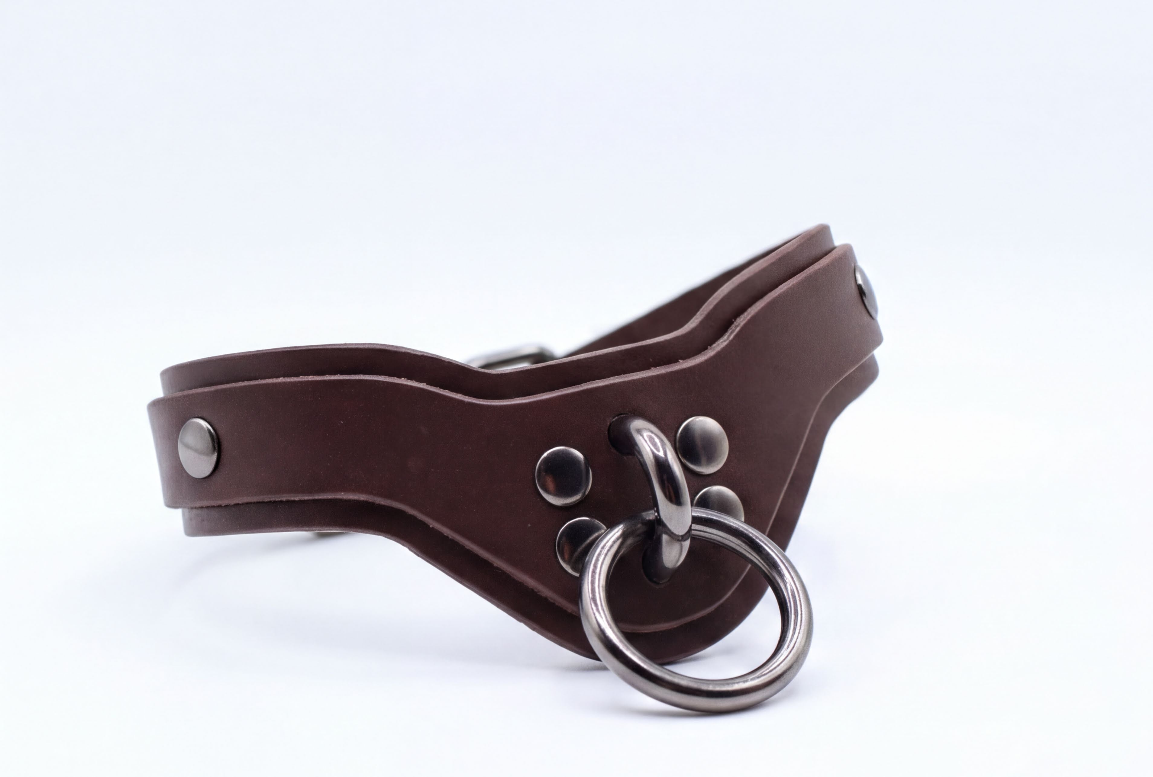 A brown leather choker collar with metal studs and a metal ring.