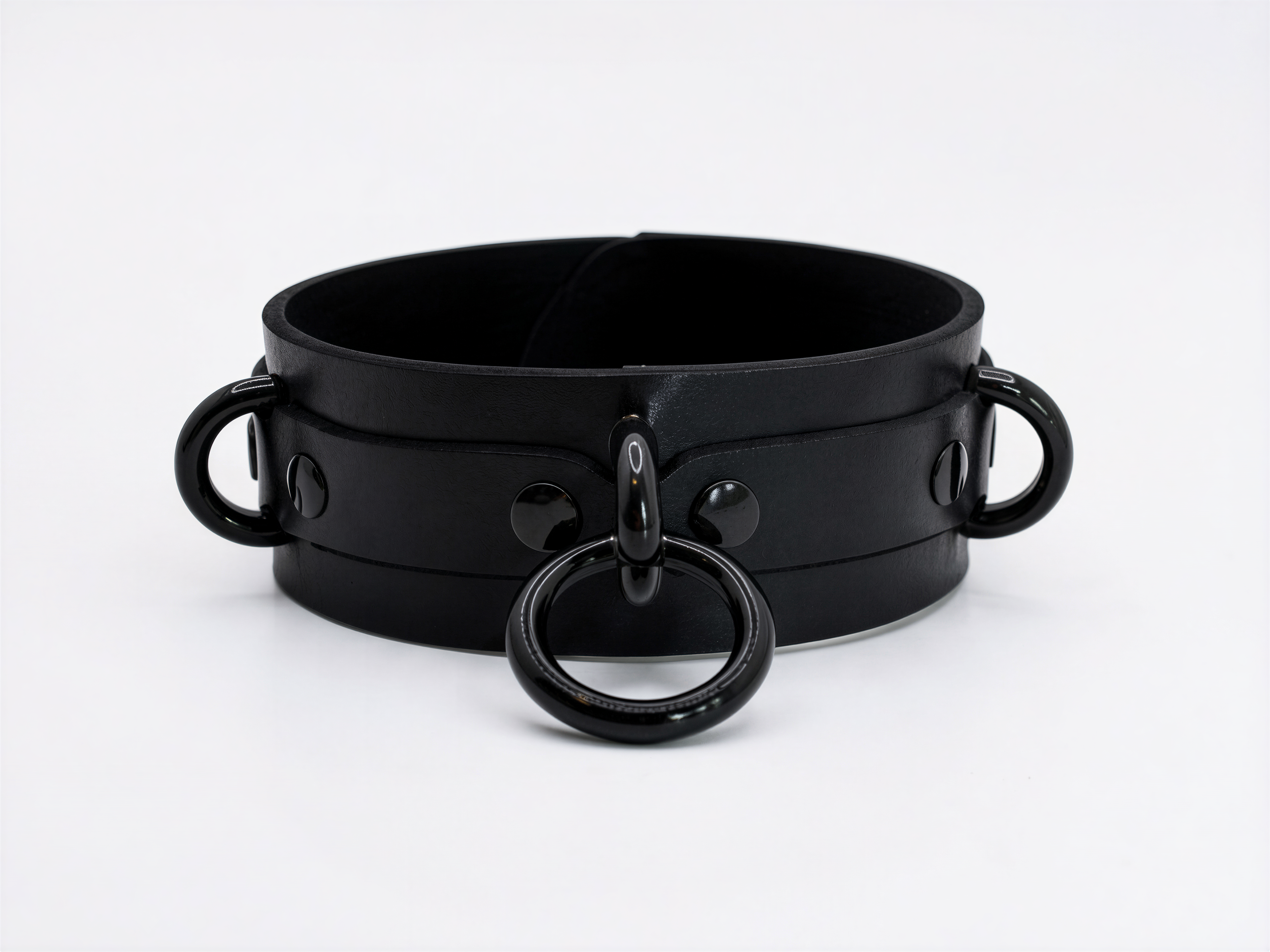 A black leather choker collar with metal rings and handles.