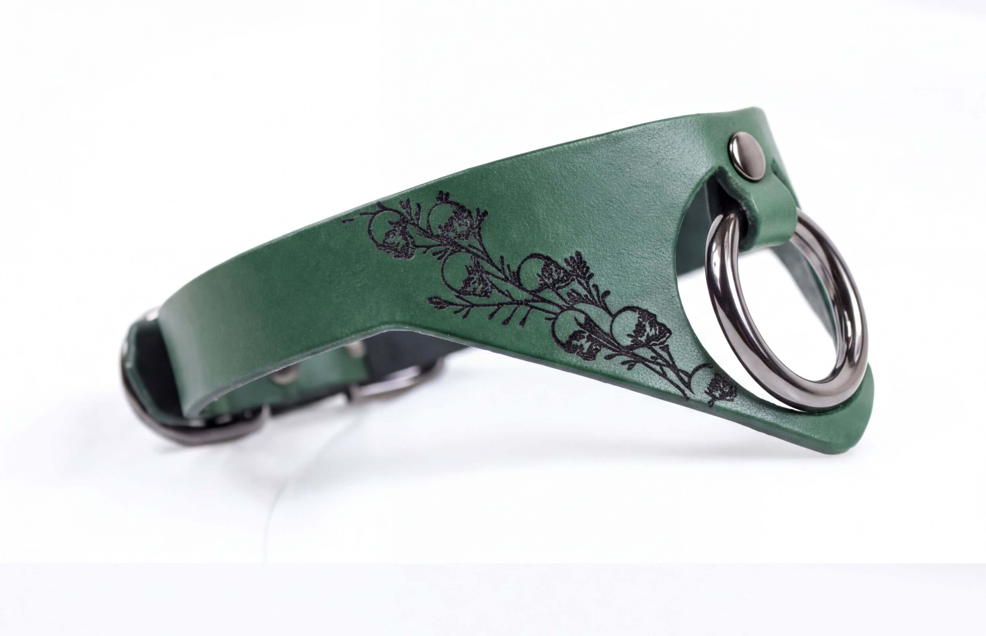 A green leather collar with a metal ring and a floral design on the side.