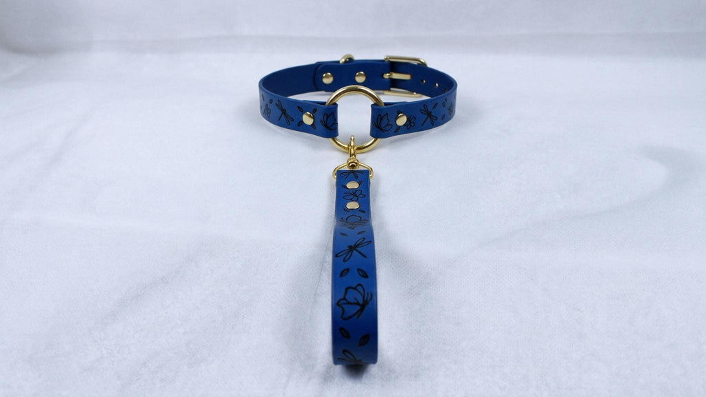 A blue collar with a gold buckle and a matching leash attached to it, resting on a white surface.