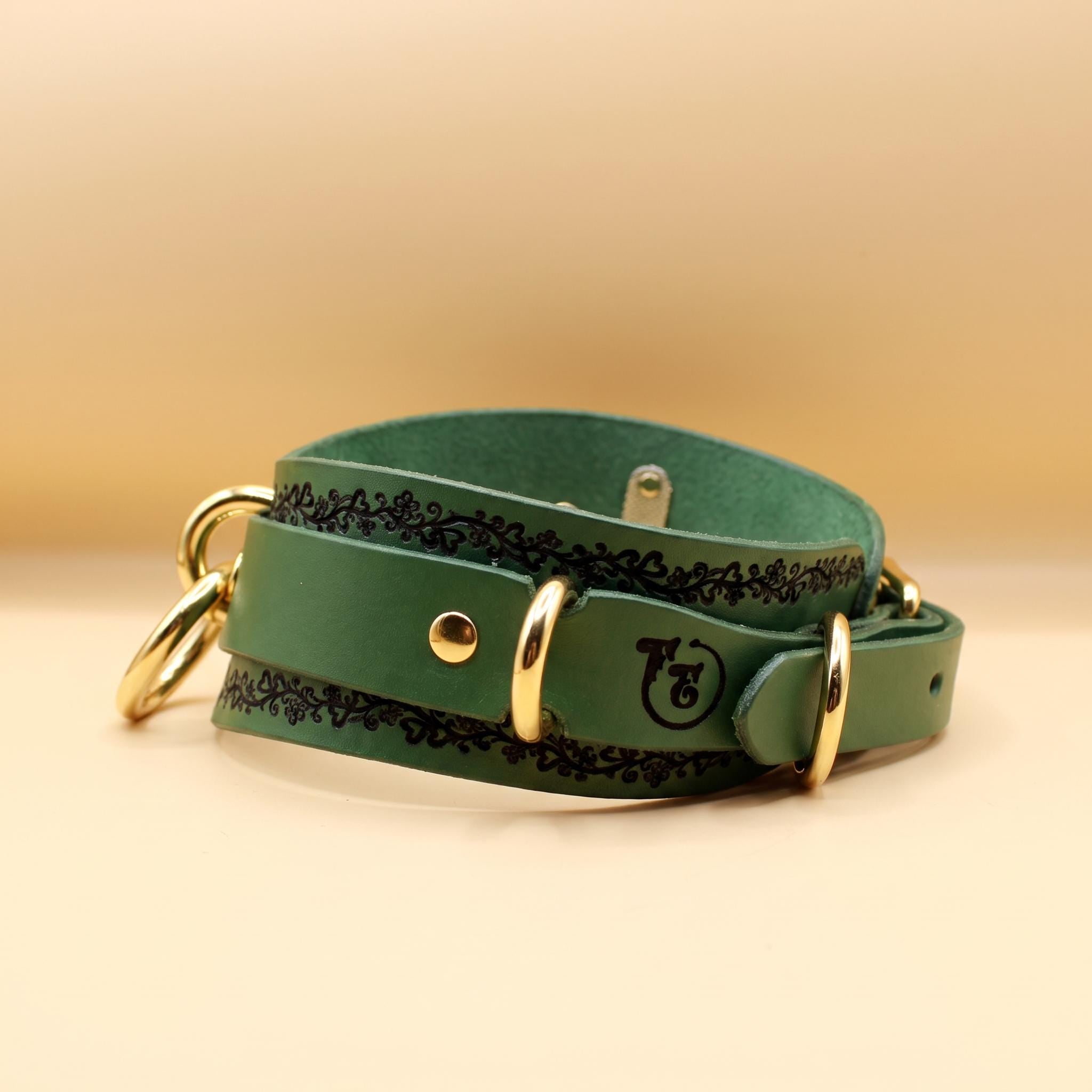 A green leather dog collar with decorative elements and gold hardware.