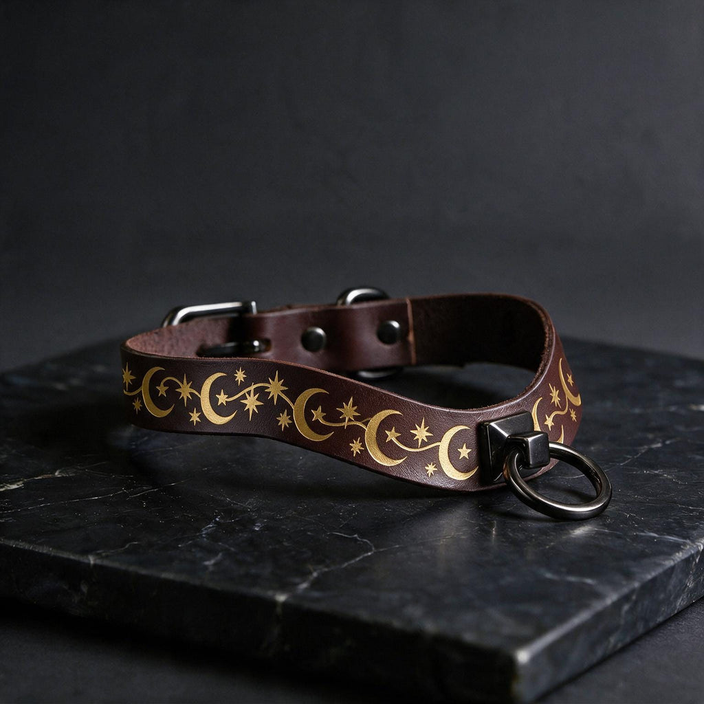 A brown leather collar with a star and crescent design on it, resting on a black surface.