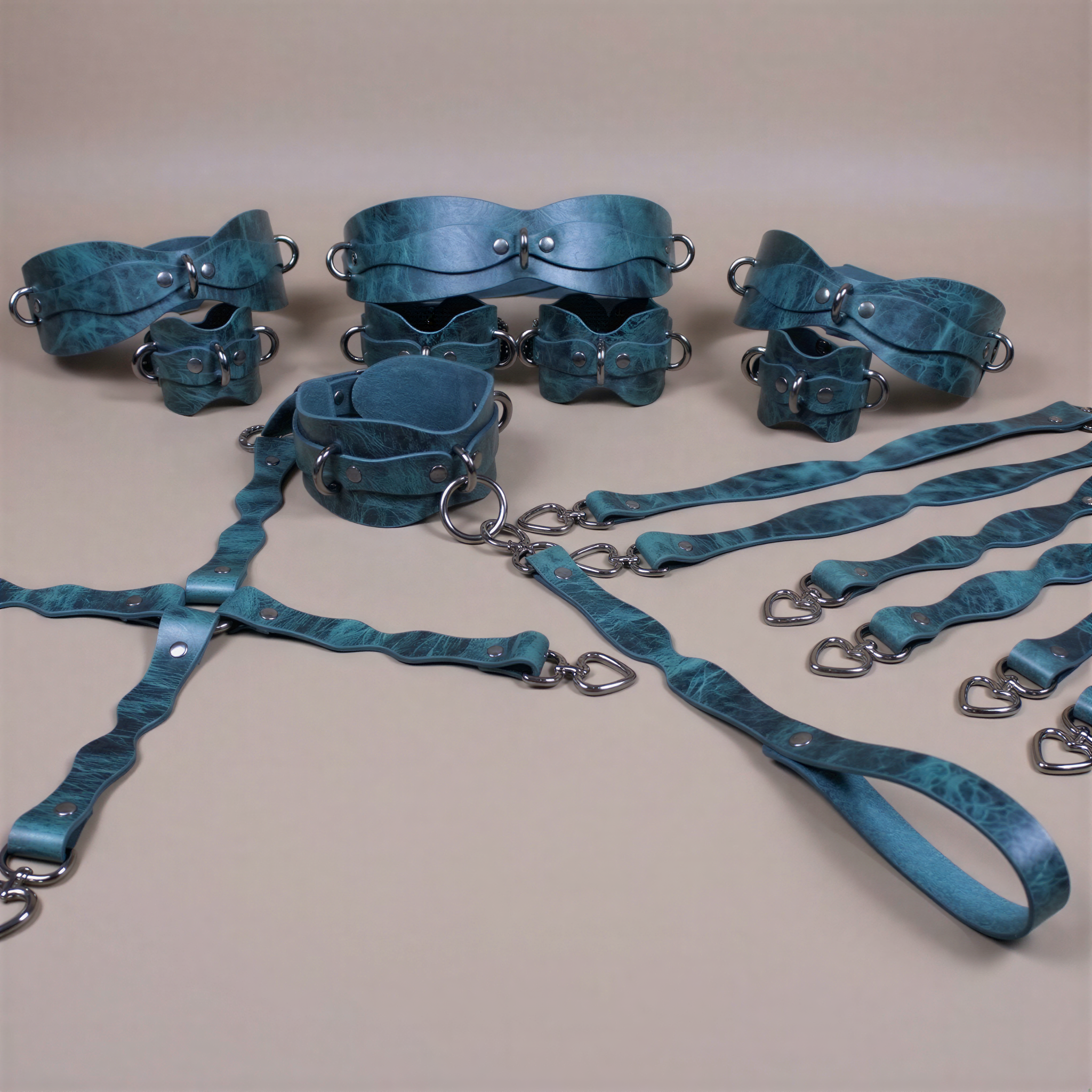 A collection of various leather straps and buckles in shades of blue and green, arranged on a beige background.