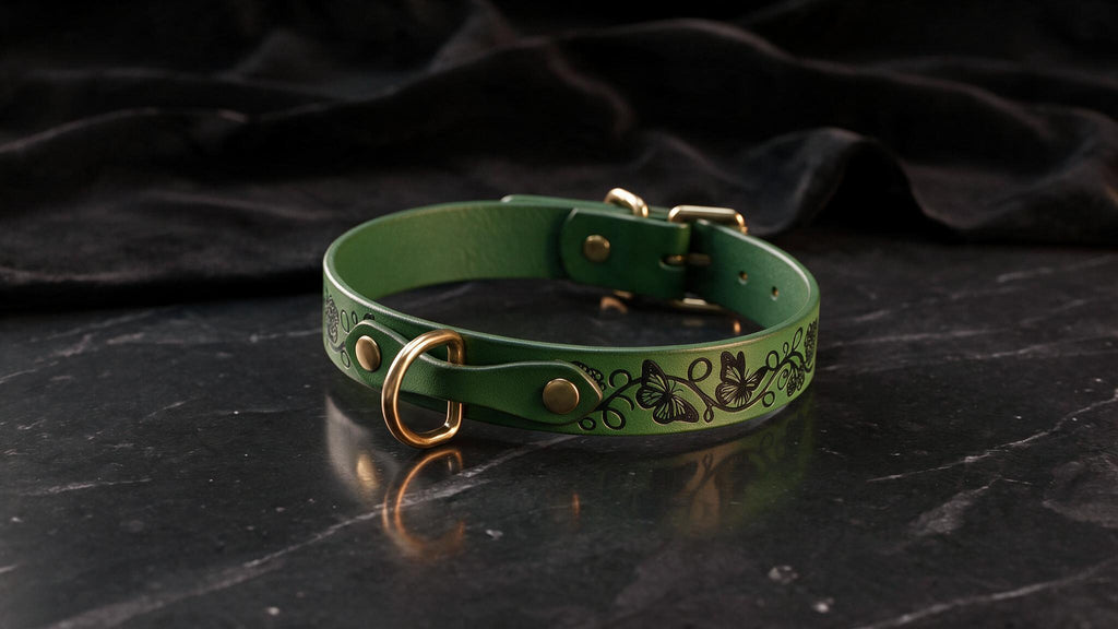 A green leather collar with a decorative pattern on it, placed on a black marble surface.