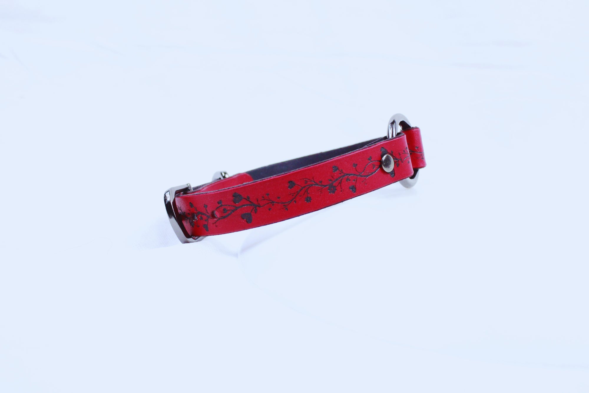 A red dog collar with a floral pattern on it.