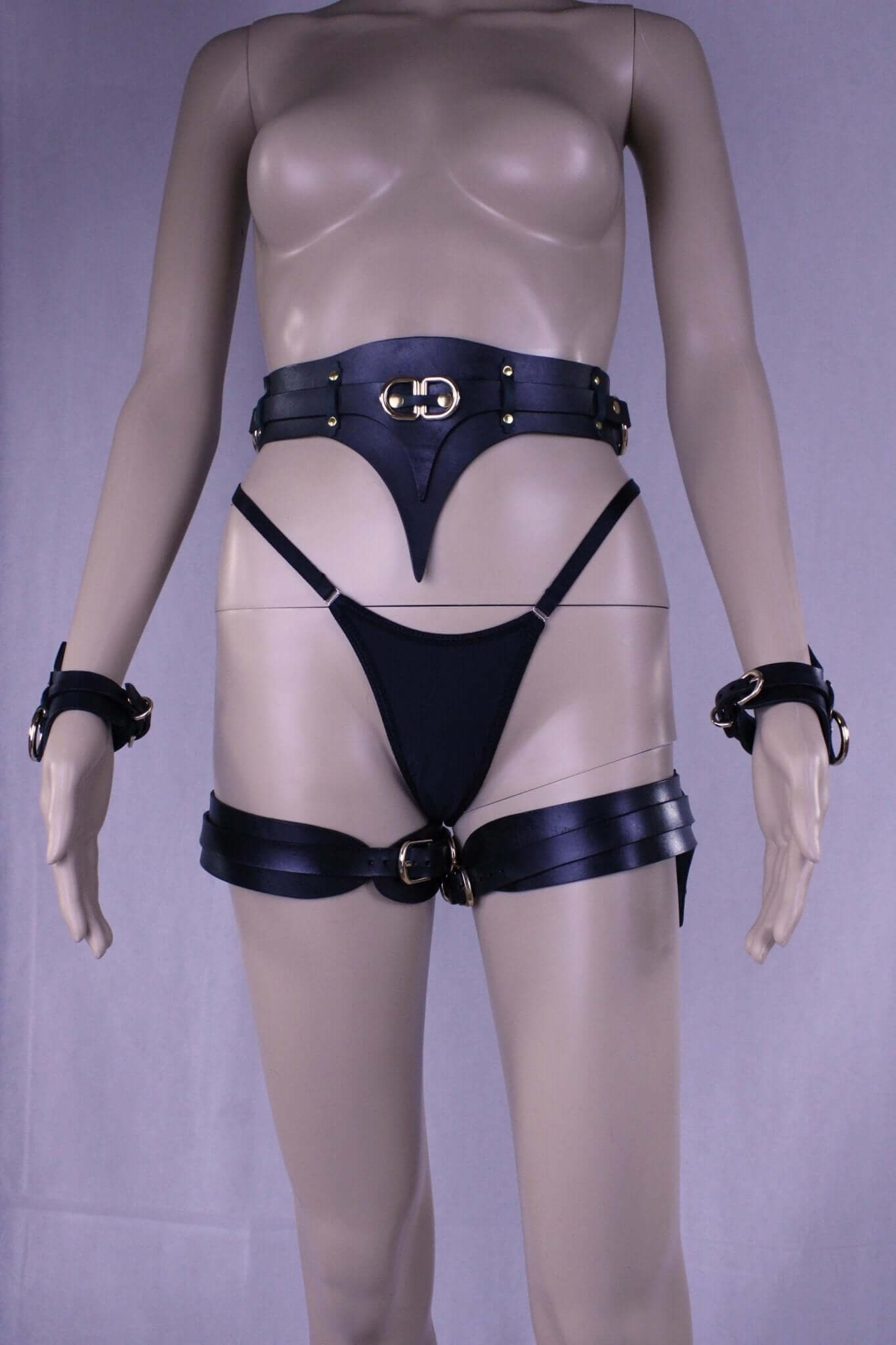 Black leather thigh harness and cuffs set, bondage gear for submissive pleasure, erotic lingerie for BDSM enthusiasts.