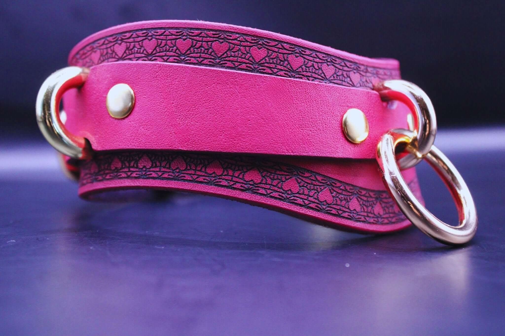 Pink leather bondage collar with gold rings, ideal for BDSM and submissive jewelry, combining elegance and allure.