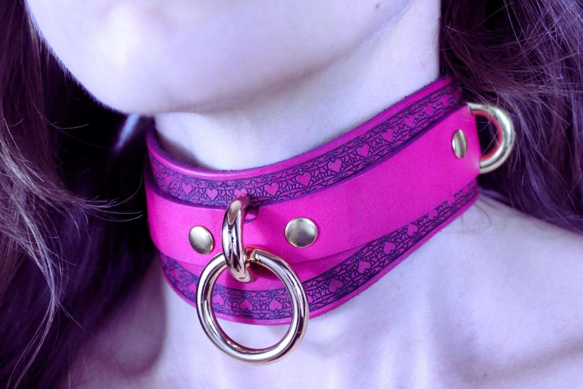 Bold pink BDSM collar featuring metal rings, ideal for submissive jewelry and discreet bondage attire.