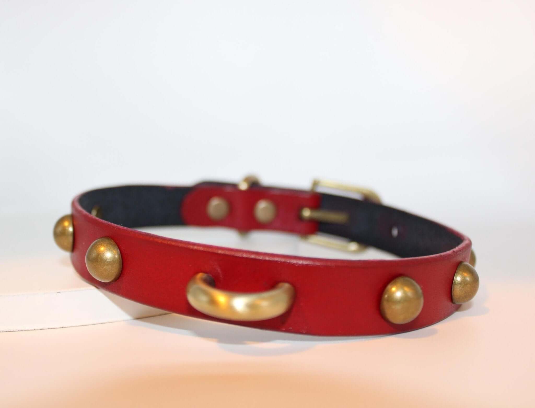 Red leather studded BDSM collar with D-ring for bondage and submissive wear, perfect for alternative fashion lovers.