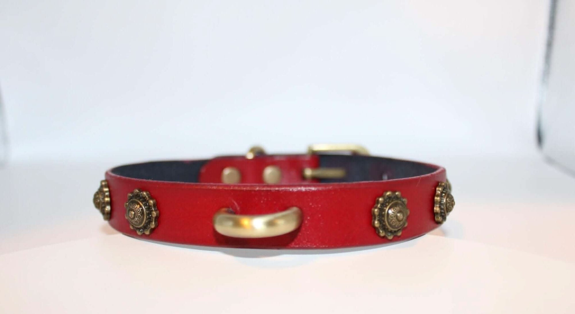 Red leather BDSM collar featuring antique-style studs and a gold-tone D-ring, perfect for submissive jewelry and alternative fashion.