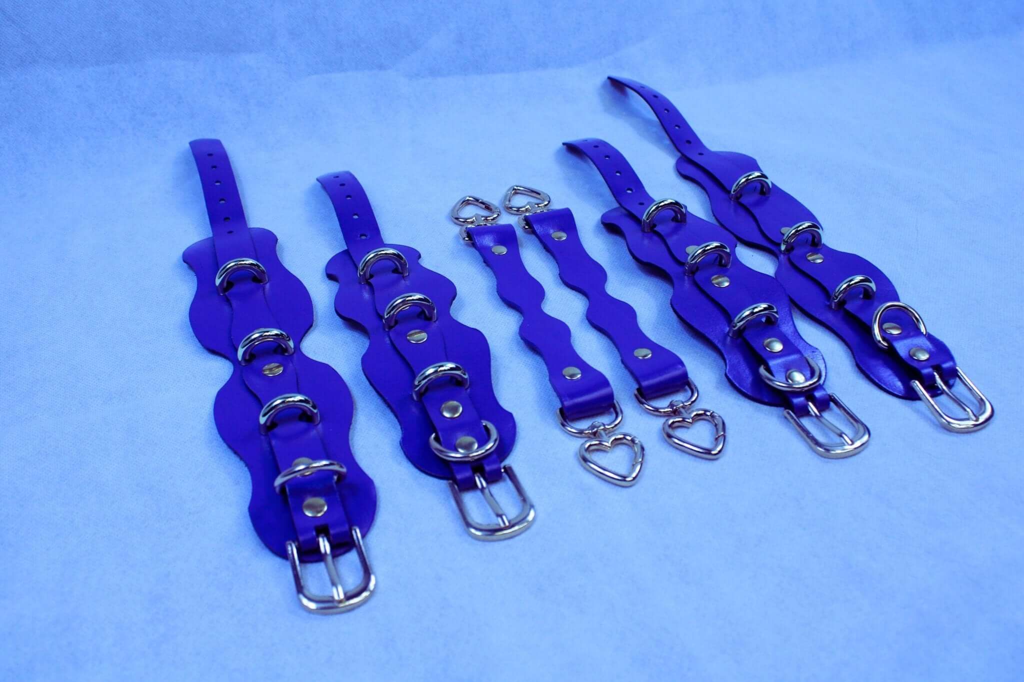 Purple leather bondage gear set with straps and rings for BDSM play, including cuffs and connectors for sub collar.