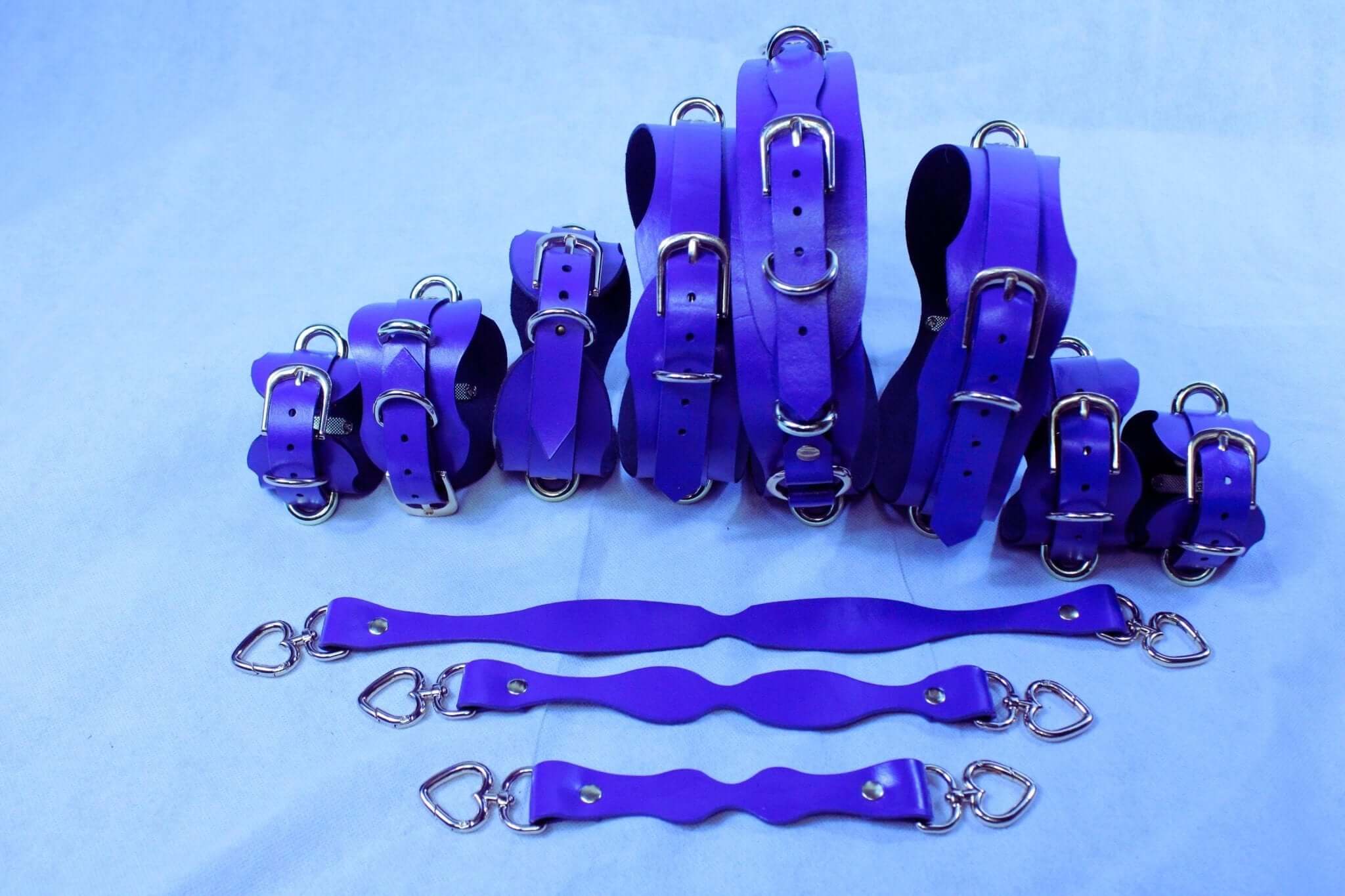 Handmade purple BDSM restraint kit featuring collars, cuffs, and straps for bondage and submissive play.