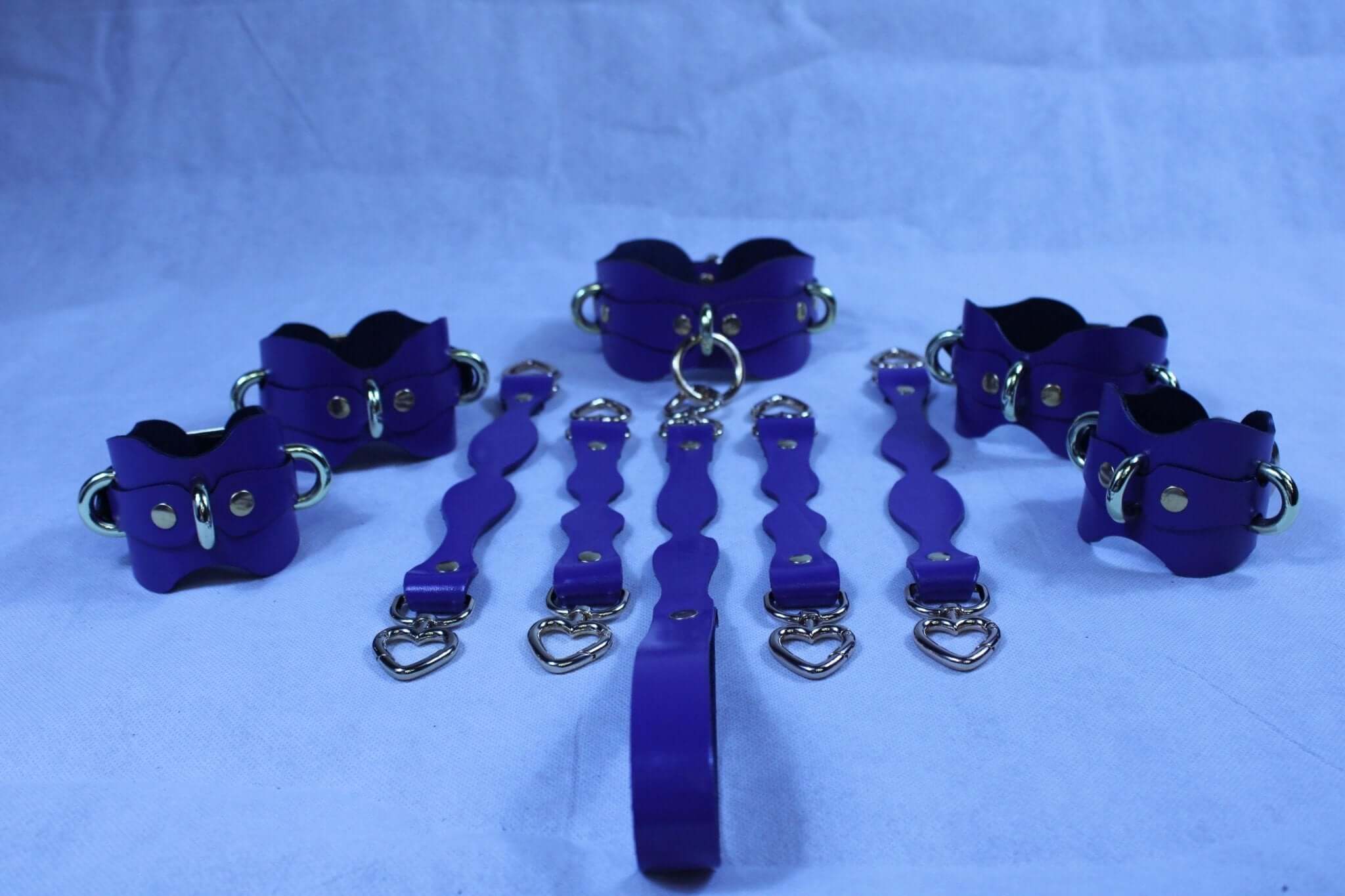 Purple leather BDSM restraint kit with cuffs and collar, perfect for submissive play and bondage gear.