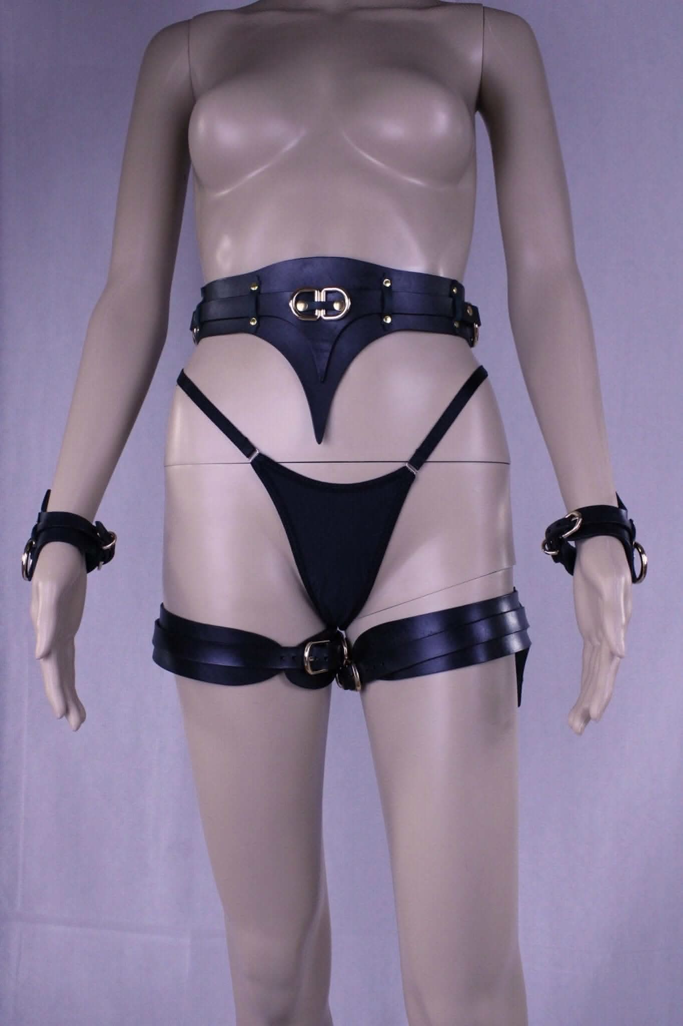 Leather thigh harness and cuffs set on mannequin, ideal for bondage gear and BDSM lingerie, enhancing intimate experiences.