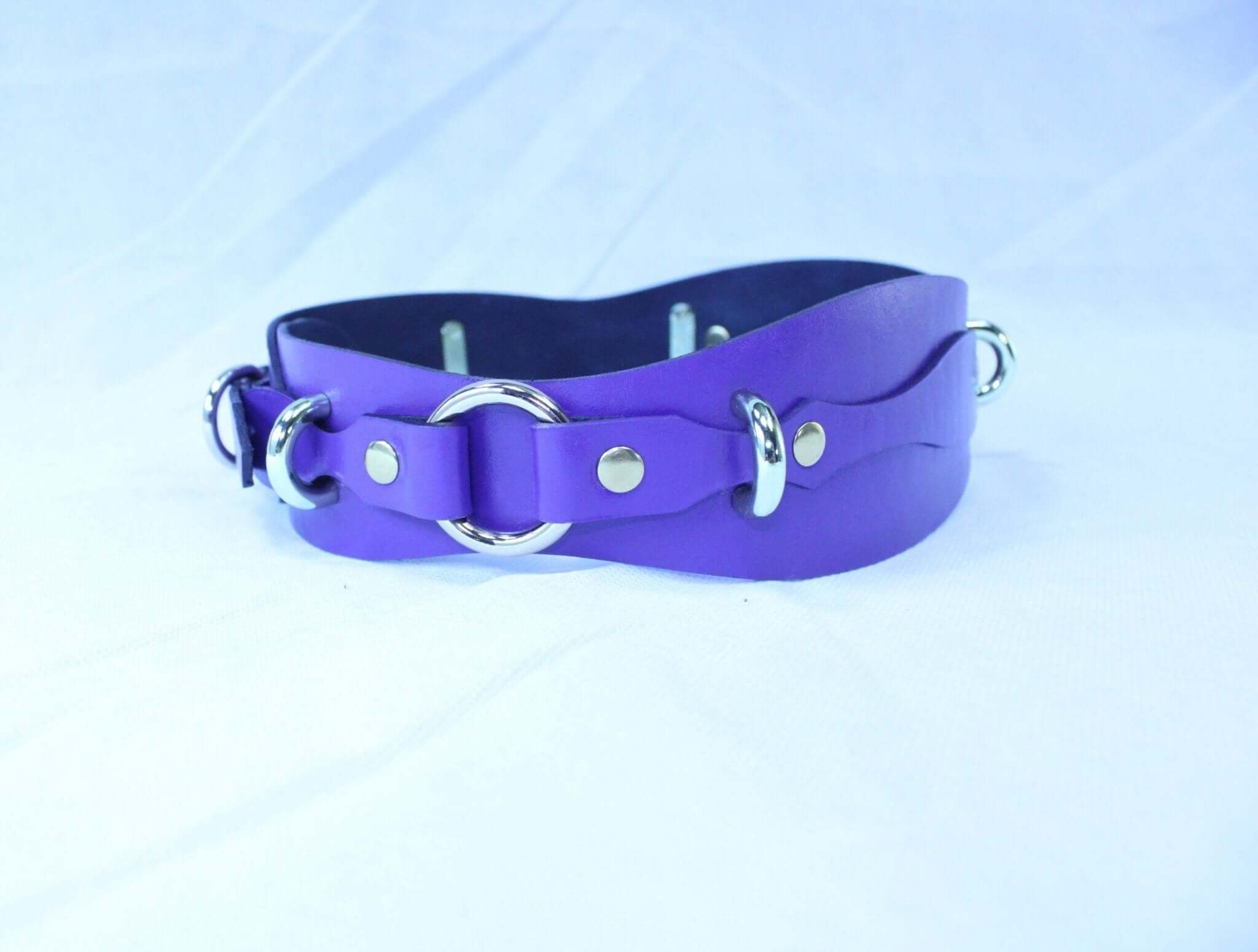 Purple leather waist belt with D-ring for bondage, adjustable restraint harness for BDSM scenes and rituals.