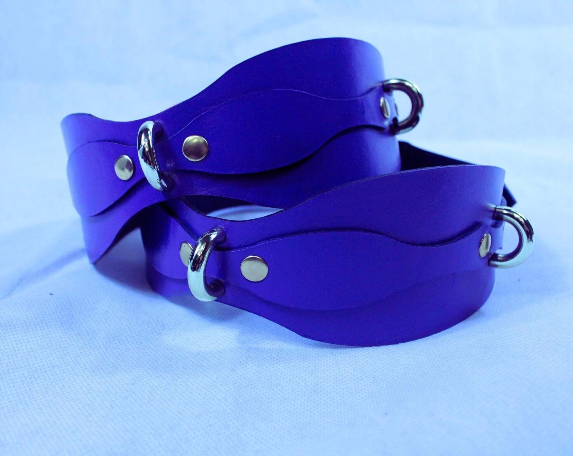 Vibrant purple leather thigh cuffs with D-rings, perfect for BDSM gear and bondage lingerie.