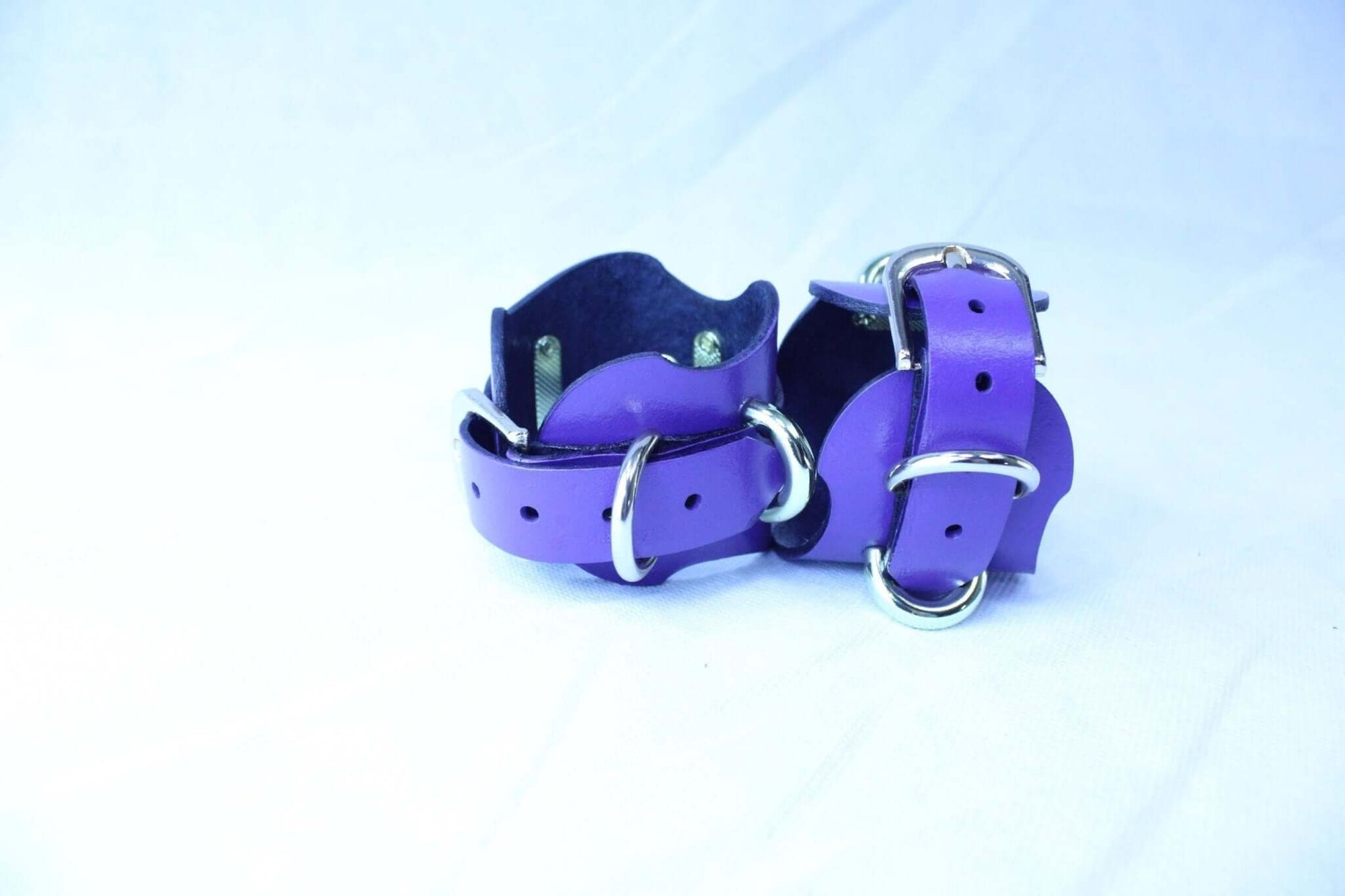 Purple handmade leather wrist cuffs with D-rings for BDSM, bondage gear, and roleplay.