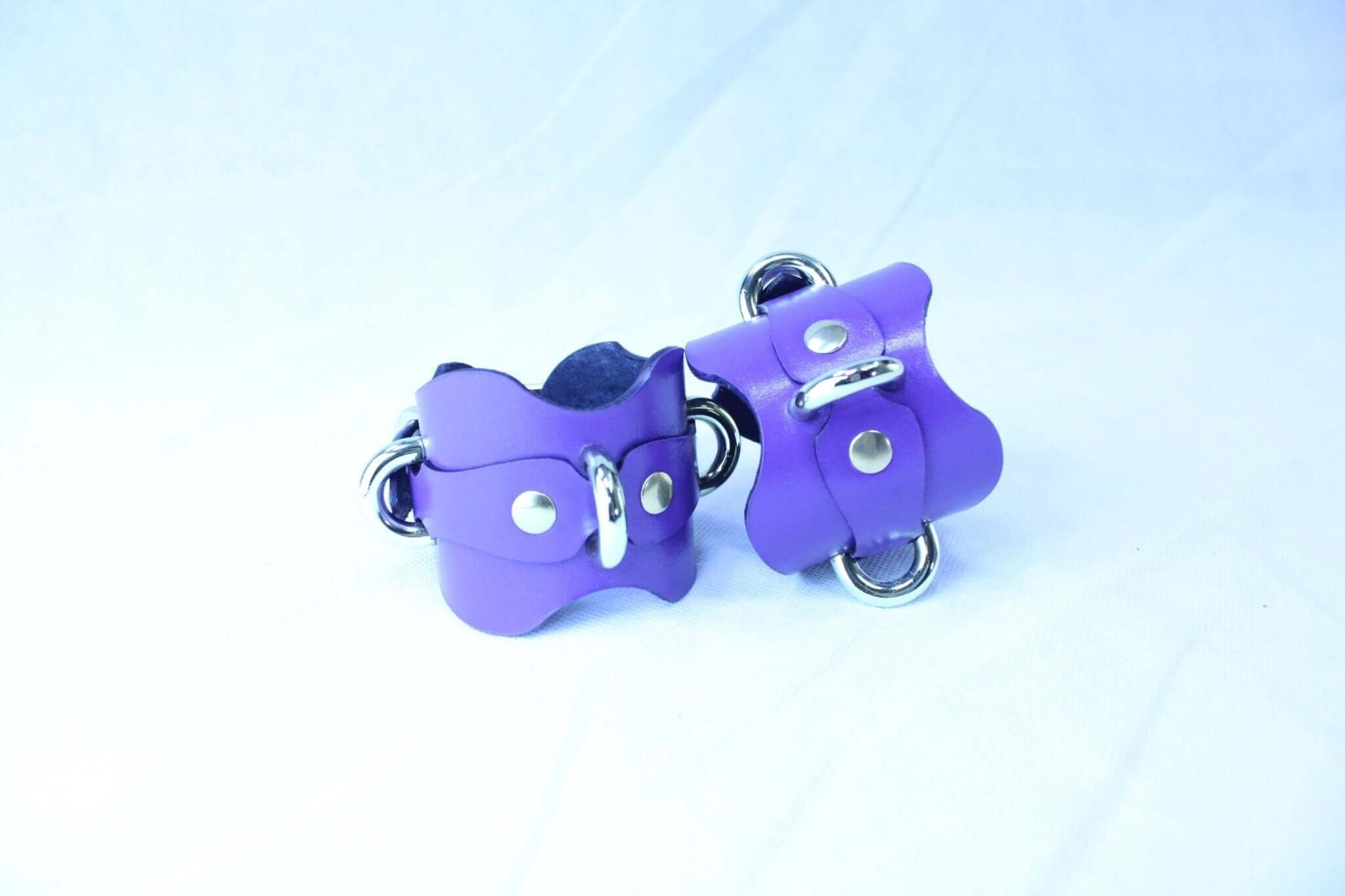 Purple handmade leather wrist cuffs with D-rings for bondage, ideal for BDSM play and roleplay accessories.