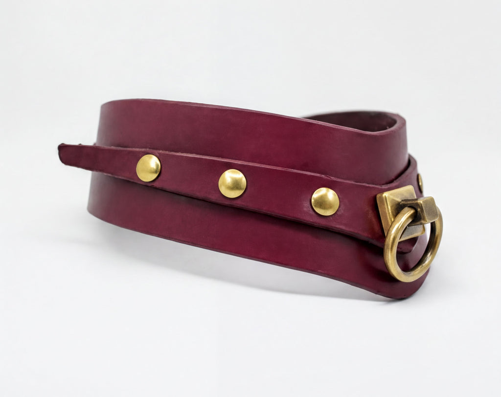 A burgundy leather choker neckerchief with a brass buckle and three gold-colored buttons.