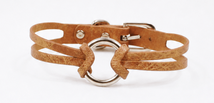 A brown leather bracelet with a metal ring and buckle.