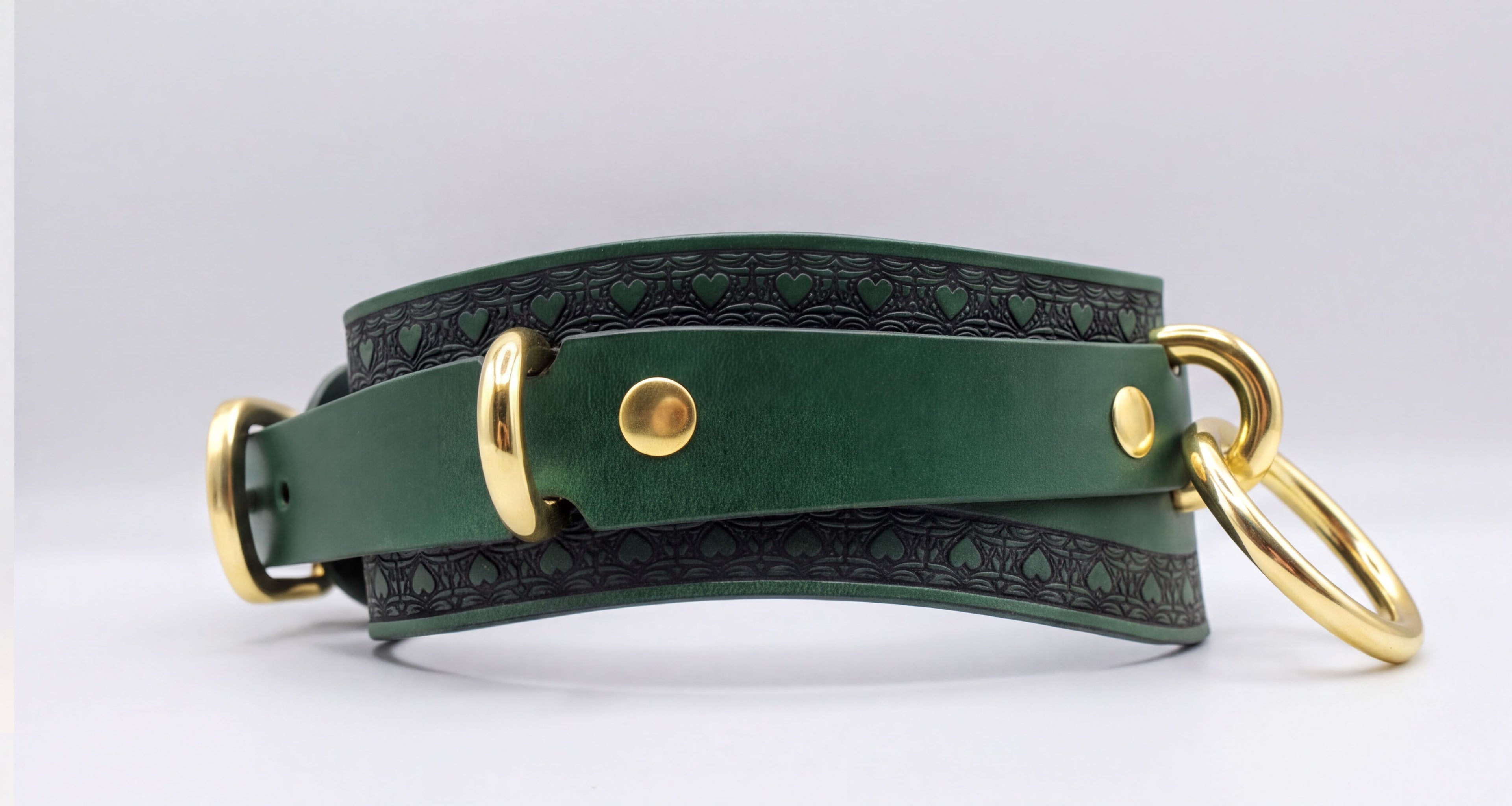 A green leather choker collar with gold hardware, including a buckle and two rings, is shown in the image.
