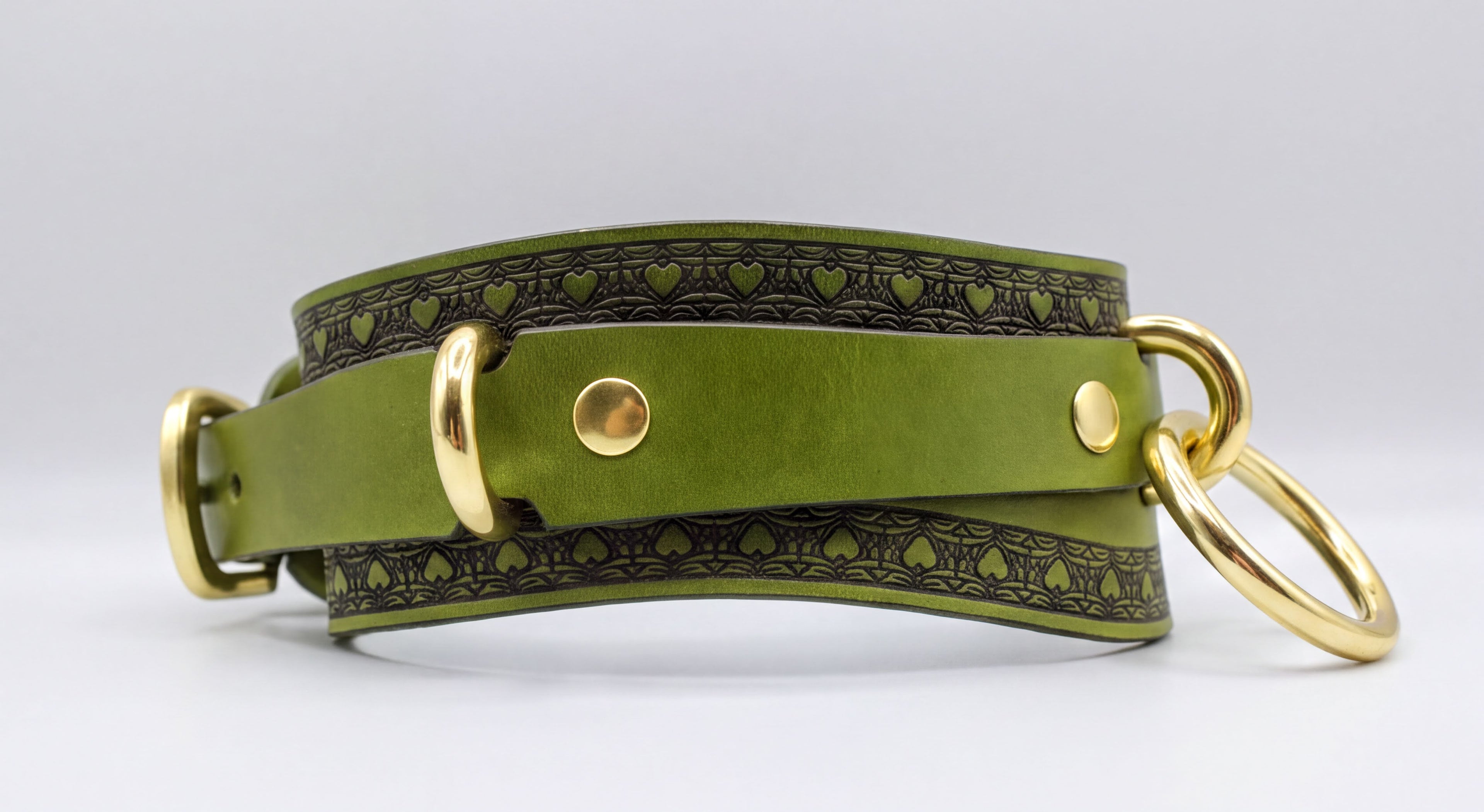 A green leather choker collar with gold hardware, including two rings and two buckles, is shown in the image.